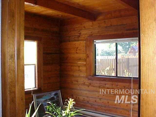 unfurnished room with beam ceiling, wooden walls, and wood ceiling