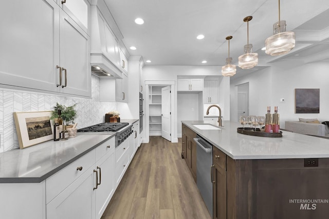 kitchen featuring stainless steel appliances, decorative light fixtures, sink, and white cabinets