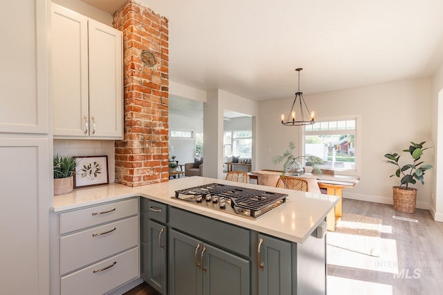 kitchen featuring kitchen peninsula, decorative backsplash, gray cabinets, and light hardwood / wood-style flooring