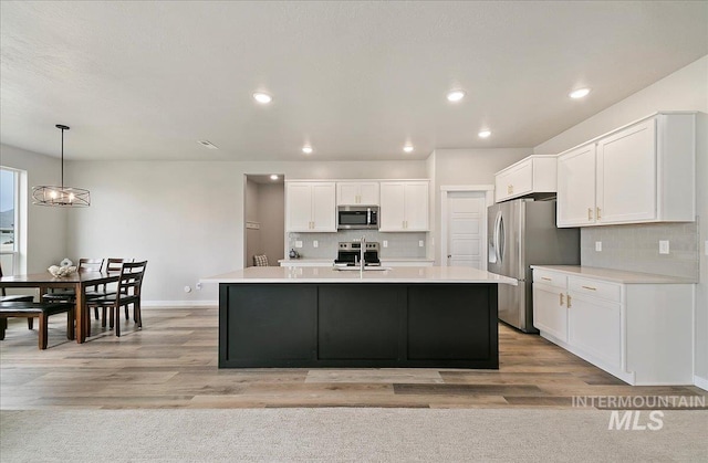 5094 W Avilla Dr, Meridian, ID 83646 - kitchen with appliances with stainless steel finishes, white cabinets, decorative backsplash, a chandelier, and baseboards