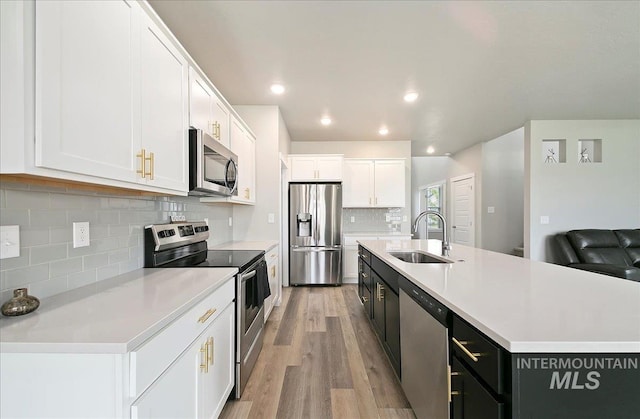 5094 W Avilla Dr, Meridian, ID 83646 - kitchen featuring appliances with stainless steel finishes, a sink, white cabinetry, dark cabinetry, and tasteful backsplash