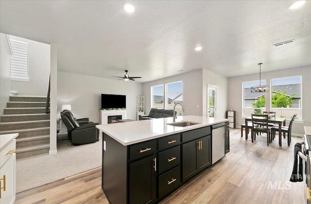 5094 W Avilla Dr, Meridian, ID 83646 - kitchen featuring a sink, dishwasher, light countertops, a warm lit fireplace, and a ceiling fan