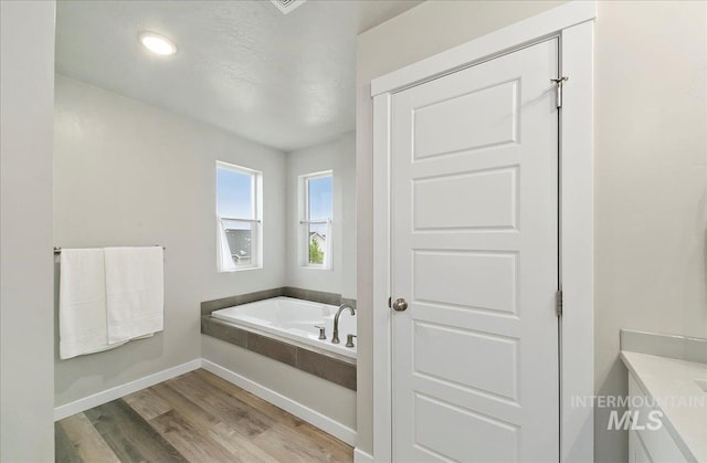 5094 W Avilla Dr, Meridian, ID 83646 - full bathroom with a garden tub, wood finished floors, and baseboards