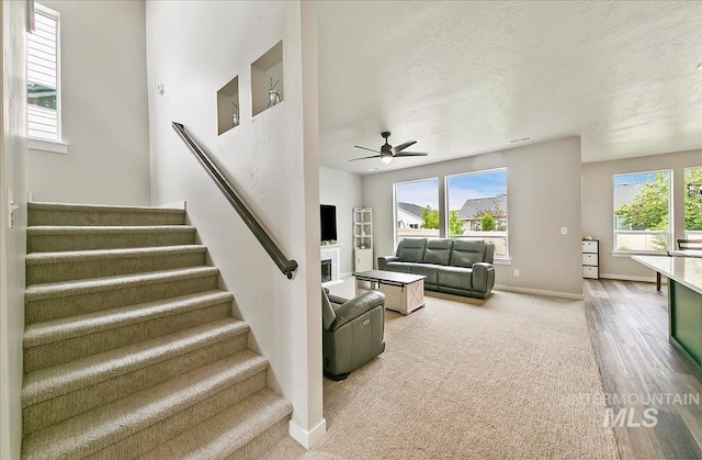 5094 W Avilla Dr, Meridian, ID 83646 - living room featuring stairs, ceiling fan, baseboards, carpet floors, and a textured ceiling