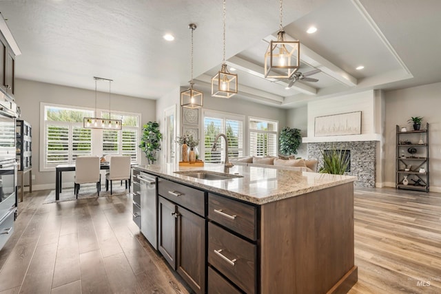 1071 W Rose Quartz St, Kuna, ID 83634 - kitchen featuring a sink, ceiling fan, wood finished floors, baseboards, and a stone fireplace