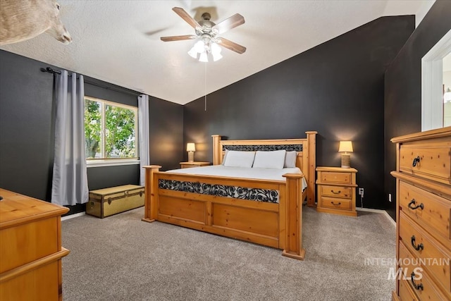 bedroom featuring a ceiling fan, carpet, vaulted ceiling, and a textured ceiling