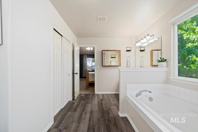 full bathroom with visible vents, ensuite bath, wood finished floors, a textured ceiling, and a bath