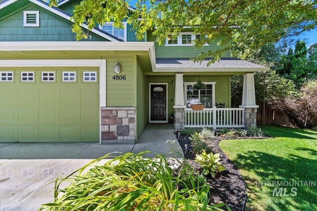 view of front of home featuring roof with shingles, a porch, an attached garage, stone siding, and a front lawn