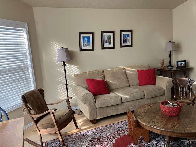 living room featuring light wood-style flooring, baseboards, and a textured ceiling