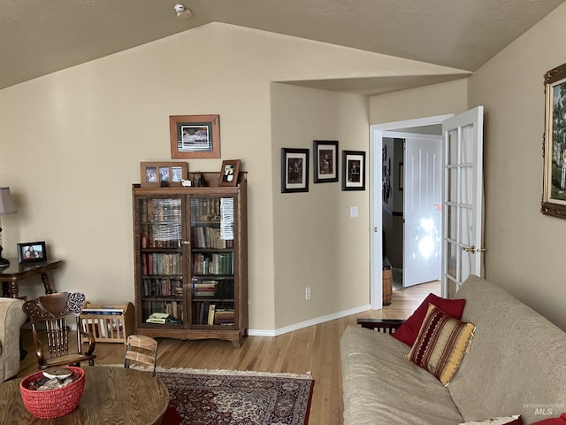 living room featuring vaulted ceiling, light wood-type flooring, and baseboards