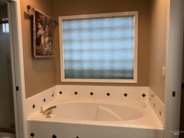 bathroom with a relaxing tiled tub and plenty of natural light