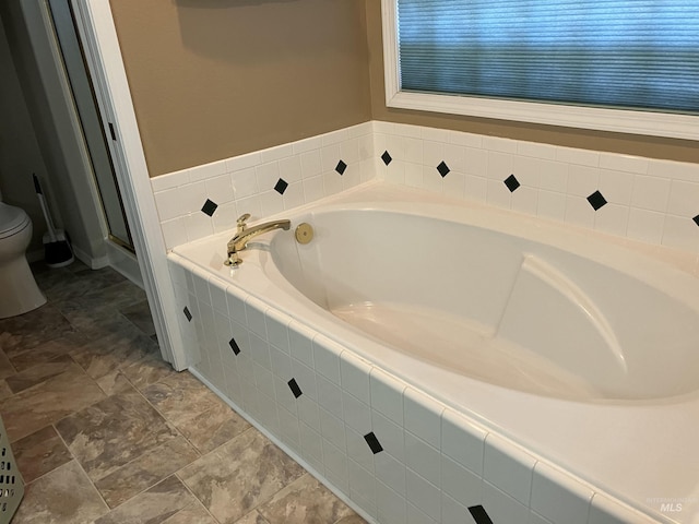 bathroom with tiled tub and toilet