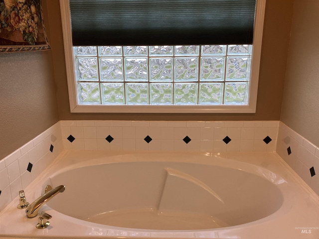 bathroom with tiled tub and a wealth of natural light