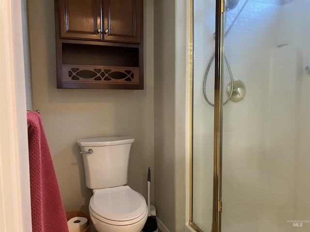 bathroom featuring a shower with shower door and toilet