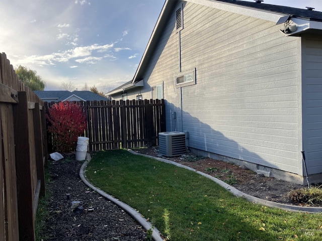 view of side of home with fence, a lawn, and central AC unit