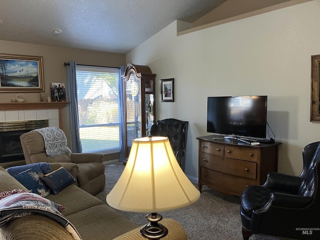 carpeted living room featuring vaulted ceiling, a tile fireplace, and a textured ceiling