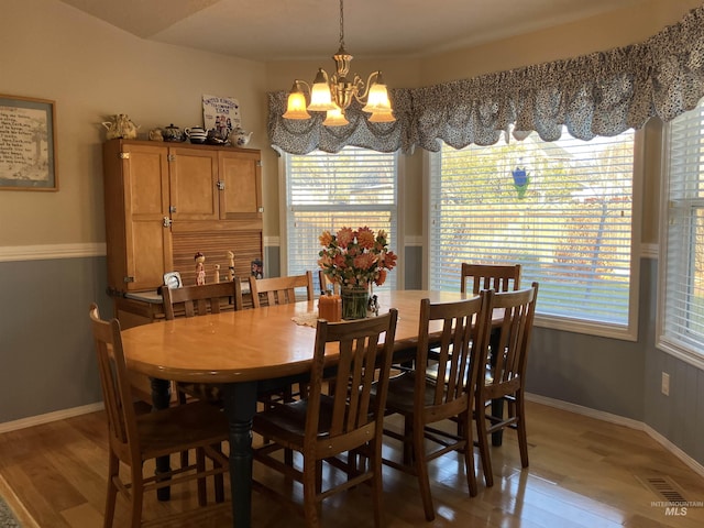 dining room featuring a chandelier, wood finished floors, visible vents, and baseboards