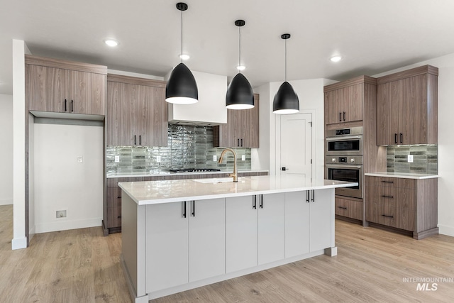 1724 Black Elm, Star, ID 83669 - kitchen with tasteful backsplash, light wood-style floors, stainless steel appliances, a center island with sink, and light countertops