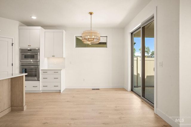 1724 Black Elm, Star, ID 83669 - kitchen with double oven, light wood finished floors, hanging light fixtures, light countertops, and white cabinetry