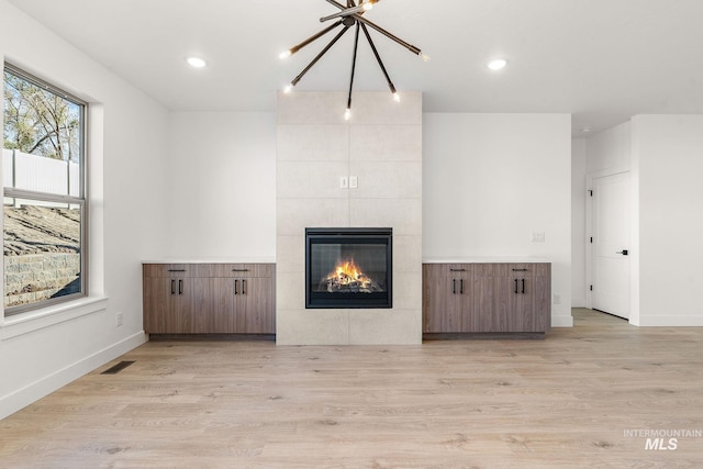 1724 Black Elm, Star, ID 83669 - unfurnished living room with visible vents, light wood-style floors, baseboards, a tiled fireplace, and a notable chandelier