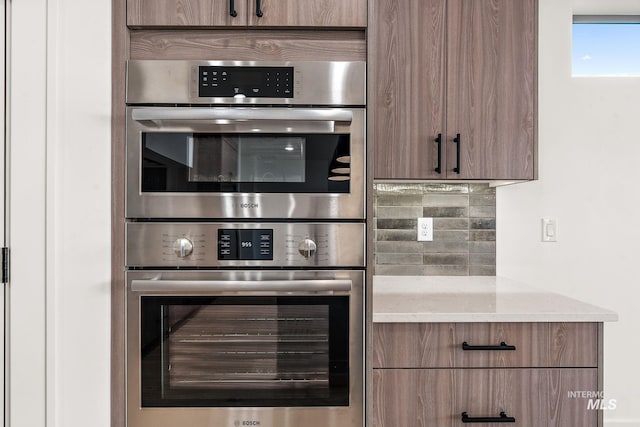 1724 Black Elm, Star, ID 83669 - kitchen featuring light stone counters, double oven, decorative backsplash, and modern cabinets