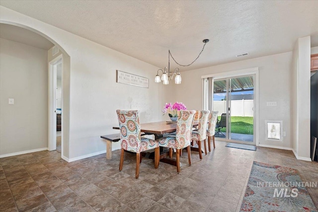 dining area featuring tile patterned floors, a notable chandelier, and a textured ceiling