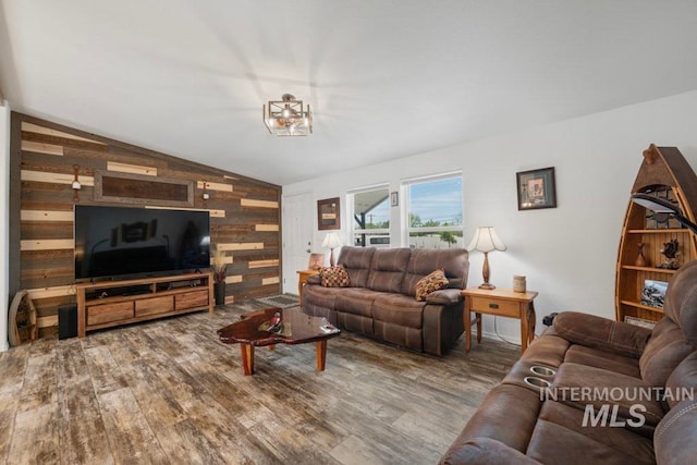 living area with lofted ceiling, wood walls, and wood finished floors