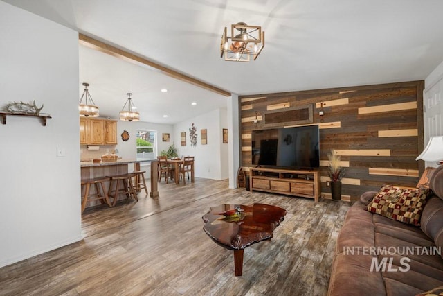 living room with a chandelier, wood walls, wood finished floors, and recessed lighting
