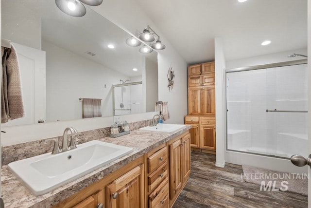 full bath featuring a shower stall, wood finished floors, double vanity, and recessed lighting