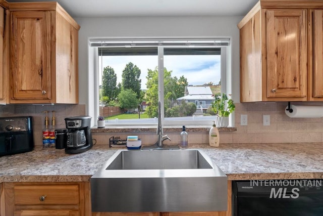 kitchen with a sink, dishwasher, light countertops, and decorative backsplash