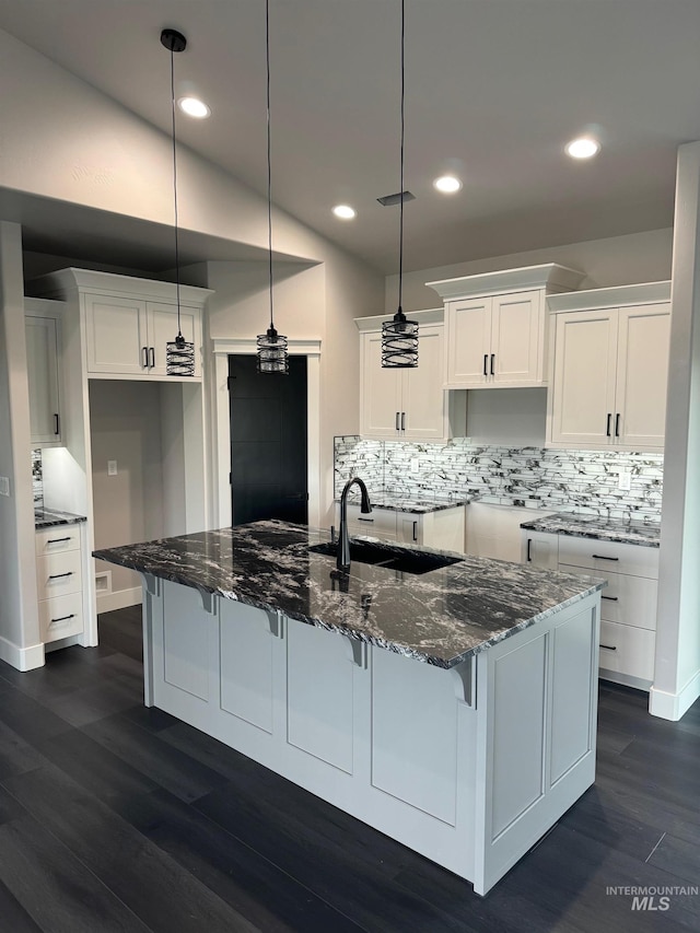 kitchen featuring dark stone counters, sink, dark hardwood / wood-style flooring, and white cabinetry