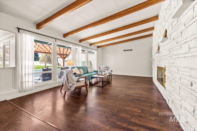 sitting room with lofted ceiling with beams, a stone fireplace, a healthy amount of sunlight, and visible vents