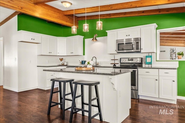 kitchen featuring appliances with stainless steel finishes, beam ceiling, and tasteful backsplash