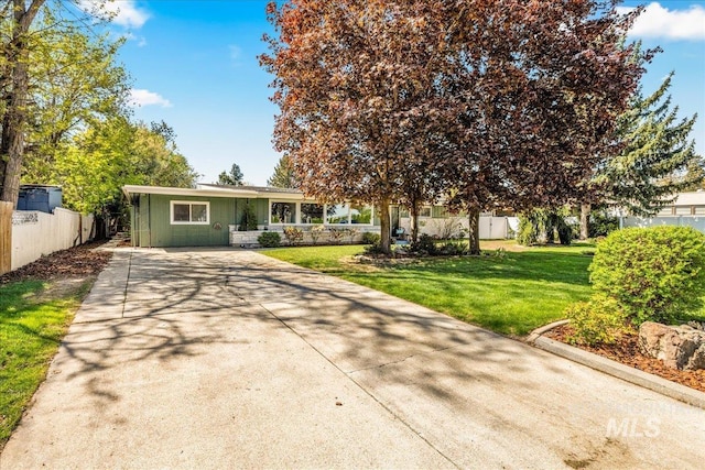 view of front of property with concrete driveway, fence, and a front yard