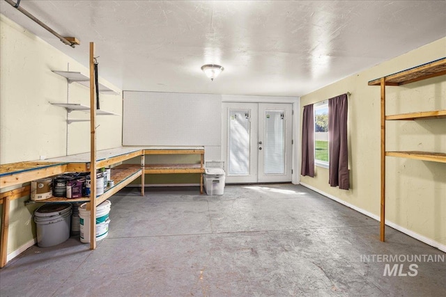 interior space with unfinished concrete floors, a workshop area, and french doors
