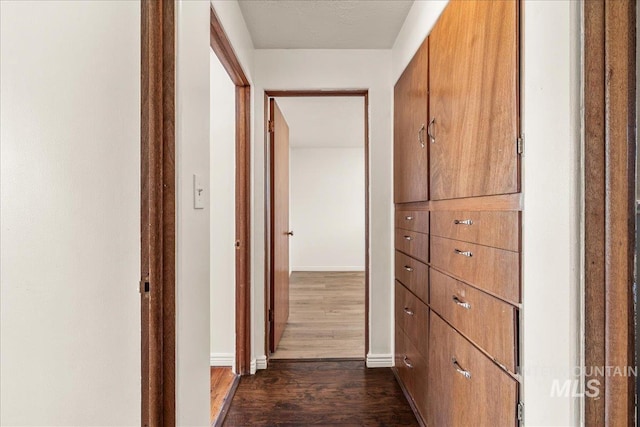 hallway with baseboards and dark wood-style flooring