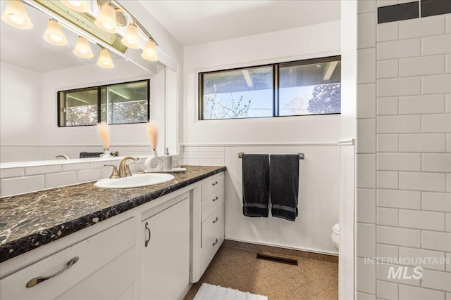 bathroom featuring wainscoting, vanity, toilet, tile patterned floors, and visible vents