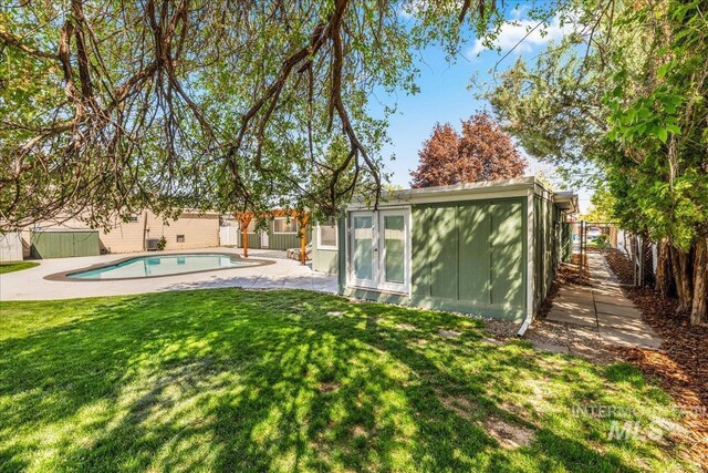 rear view of property with a fenced in pool, a fenced backyard, a lawn, and an outdoor structure