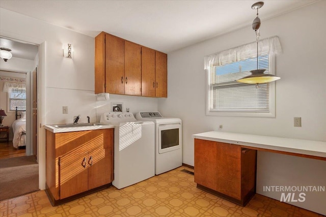 clothes washing area with sink, separate washer and dryer, and cabinets