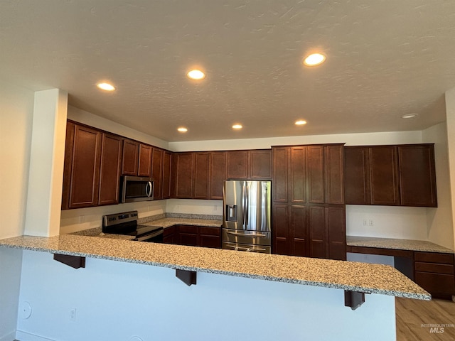 5619 E Bollo St, Nampa, ID 83687 - kitchen featuring stainless steel appliances, a peninsula, light stone countertops, a breakfast bar, and recessed lighting