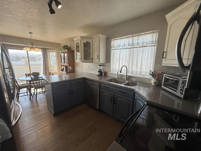 kitchen with dark wood-style floors, decorative backsplash, stainless steel appliances, and a sink