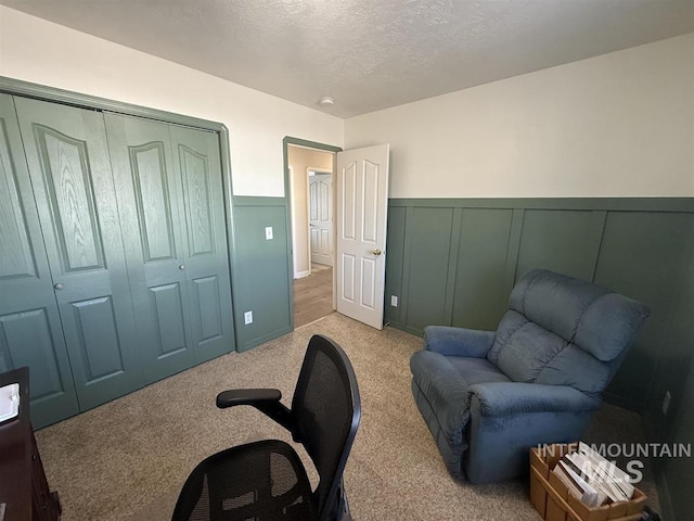 home office featuring a wainscoted wall, a textured ceiling, and light colored carpet