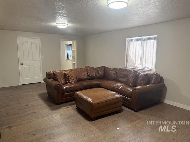 living room featuring a textured ceiling, wood finished floors, and baseboards