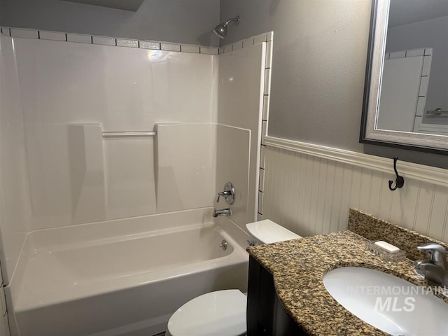 bathroom with a wainscoted wall, vanity, toilet, and tub / shower combination