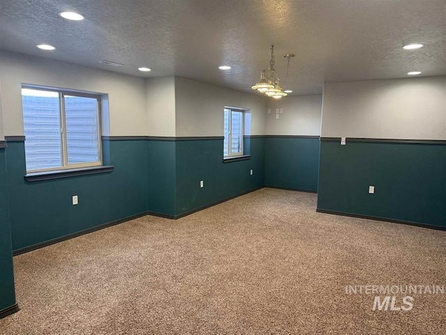 carpeted empty room with a wainscoted wall, a textured ceiling, and recessed lighting