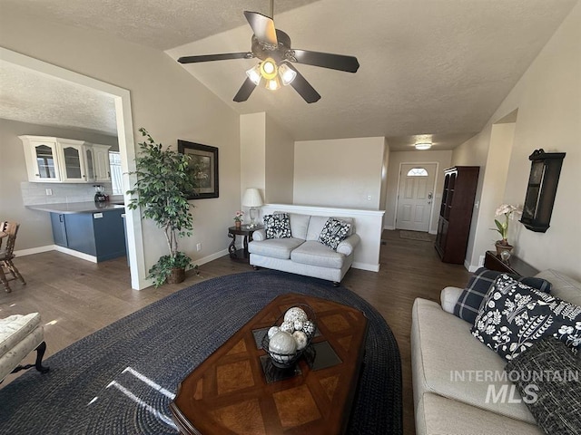 living room featuring lofted ceiling, a textured ceiling, wood finished floors, and baseboards