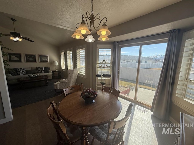 dining room with vaulted ceiling, a textured ceiling, wood finished floors, and a healthy amount of sunlight