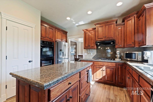 kitchen with stainless steel appliances, under cabinet range hood, light wood-style floors, backsplash, and recessed lighting