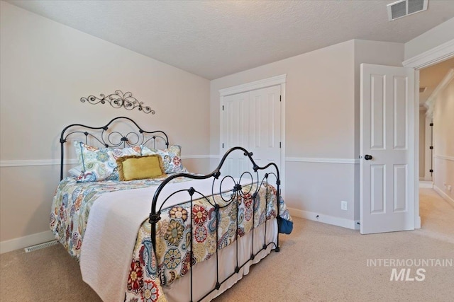bedroom with carpet flooring, baseboards, a textured ceiling, and a closet