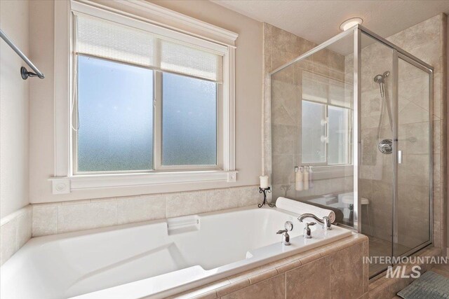 full bathroom with healthy amount of natural light, a stall shower, and a garden tub